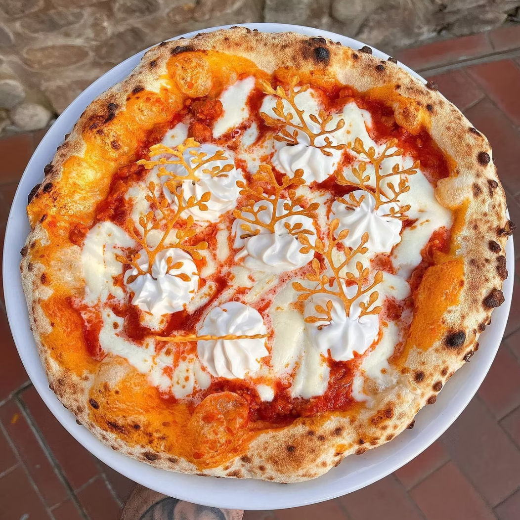 Overhead view of Neapolitan pizza with decorative pastry and cream